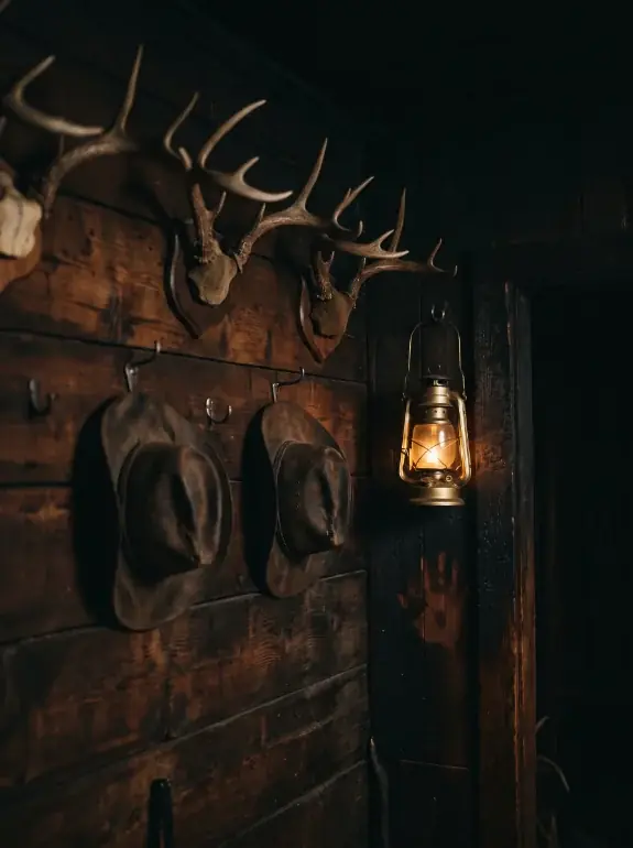 AI image: antlers, hats and a burning lantern on the wooden wall
